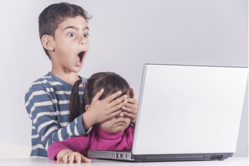 brother covering up sisters seeing while looking on laptop