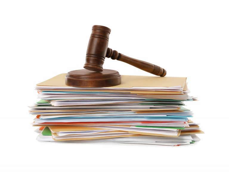 A wooden gavel sits on top of a stack of documents.