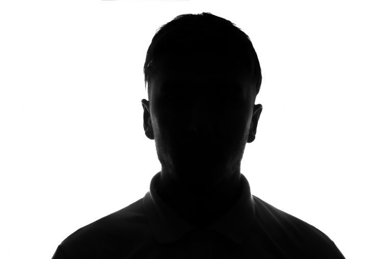 A silhouette of a man in a white shirt, raising questions about why are mugshots public.